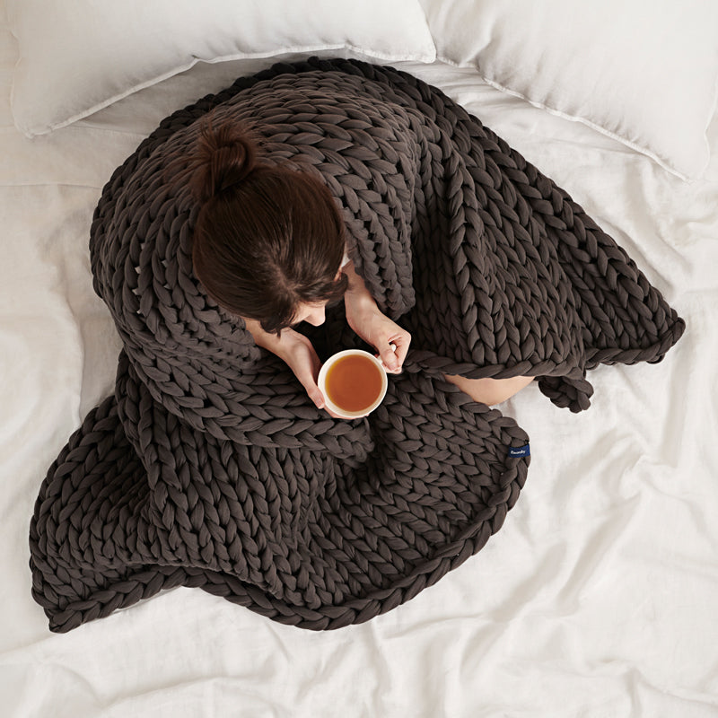 Lady under the gentle weight of the Cotton Napper with a cup of tea